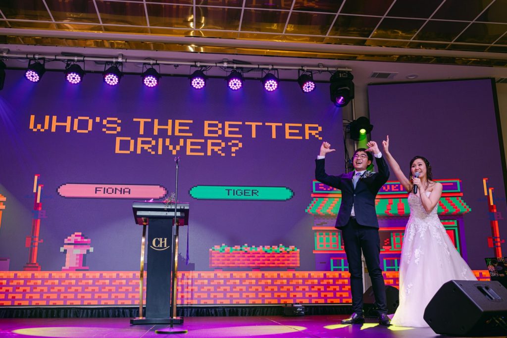 bride and groom play video game style powerpoint on stage at Canton House