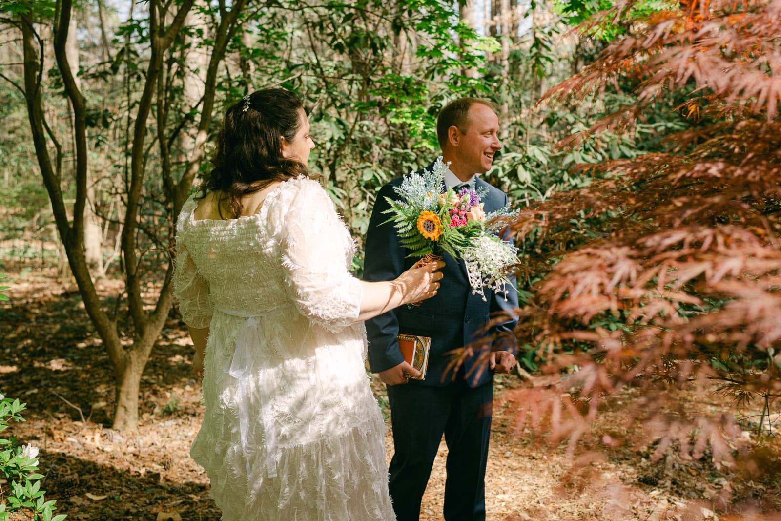 married couple stands together in woods at Woodlands Garden
